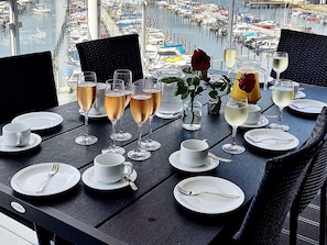A table set for dining with glasses of champagne, a rose, and a view of a marina with boats. - 5 Star Holiday Home in Wendtorf (Wendtorf)