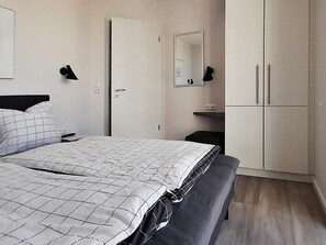 A bedroom with a bed, a wardrobe, a bedside table, and a mirror. - 5 Star Holiday Home in Wendtorf (Wendtorf)