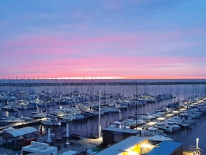 A marina with numerous boats docked, a clear sky, and a sunset.