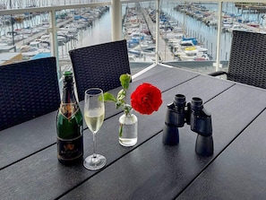 A table with a bottle, a glass, a vase with a red flower, and binoculars.