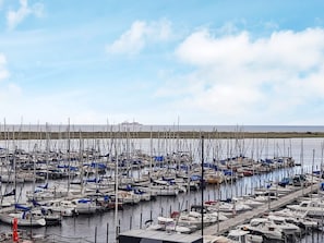 A marina with numerous boats docked in rows, a clear sky, and a calm sea in the background.