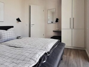 Une chambre à coucher comprenant un lit, une armoire, une table de chevet et un miroir.