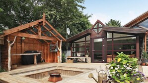 A wooden deck with a hot tub, outdoor furniture, and potted plants.
