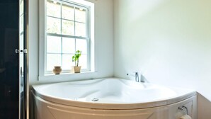 A bathroom with a freestanding bathtub, a window, and a toilet.
