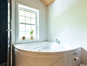 Une salle de bain avec une baignoire sur pieds, une fenêtre et des toilettes.