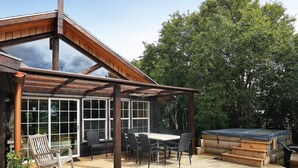 A wooden deck with a pergola, outdoor seating, and a hot tub.