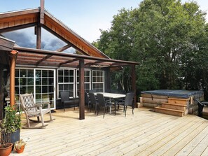 Une terrasse en bois avec une pergola, des sièges d’extérieur et un jacuzzi.