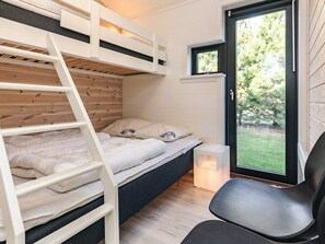 A compact room with a bunk bed, a small desk, and a window with a view of greenery. - 9 Person Holiday Home in Vaeggerlose (Vaeggerlose)