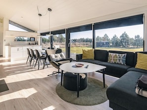 A modern living space with a dining area, a sofa, and a kitchen.