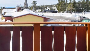 A wooden balcony railing overlooking a snowy landscape with buildings and a church in the background. - 8 Person Holiday Home in Loten-by Traum (Loten)