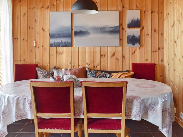Ett rum med träpanel på väggarna, ett runt bord, två stolar och en hängande lampa.