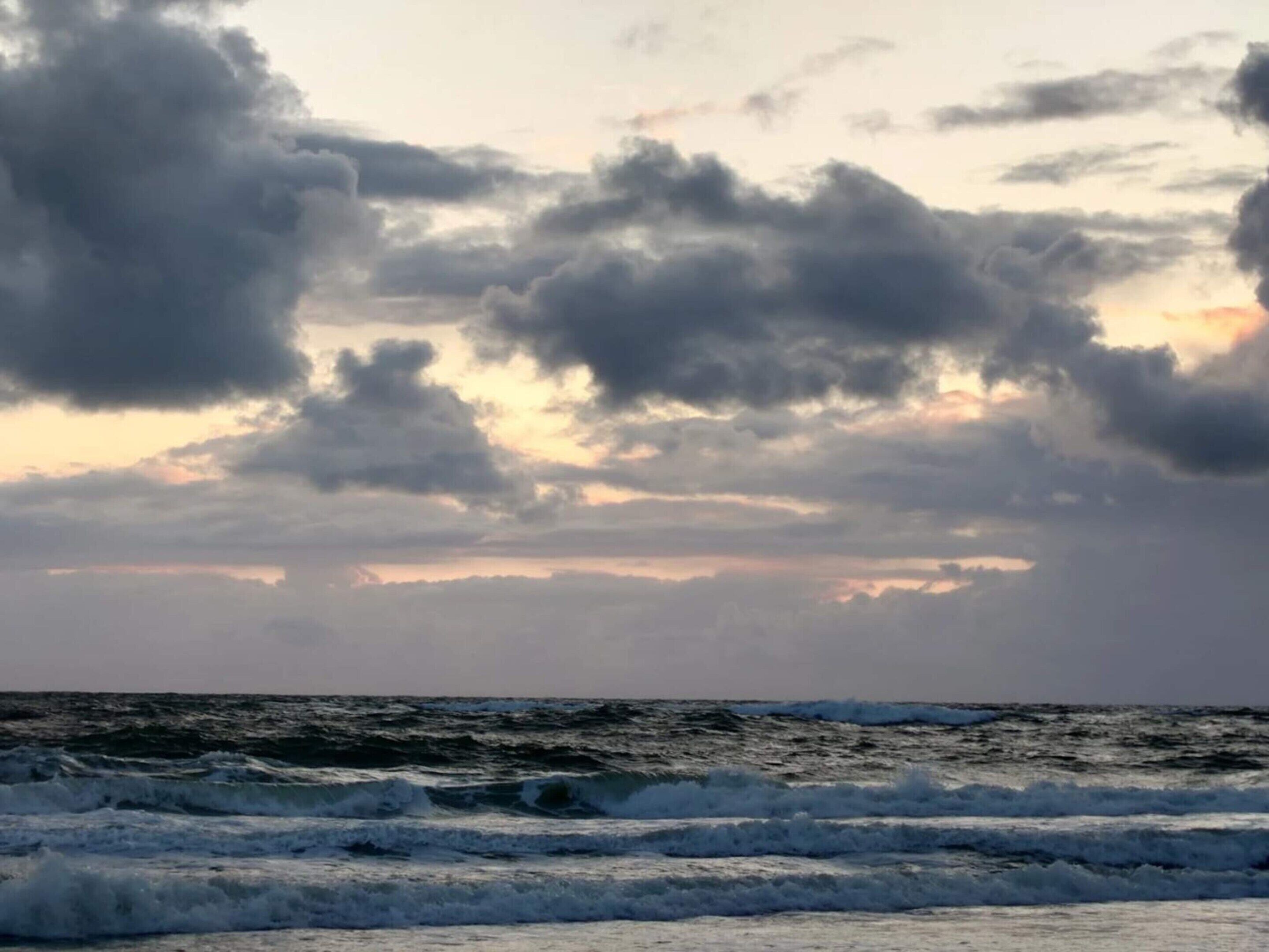 A view of the ocean with waves and a cloudy sky.