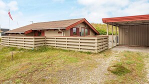 A single-story building with a sloped roof, a fenced area, and a covered porch. - 6 Person Holiday Home in Hvide Sande (Hvide Sande)