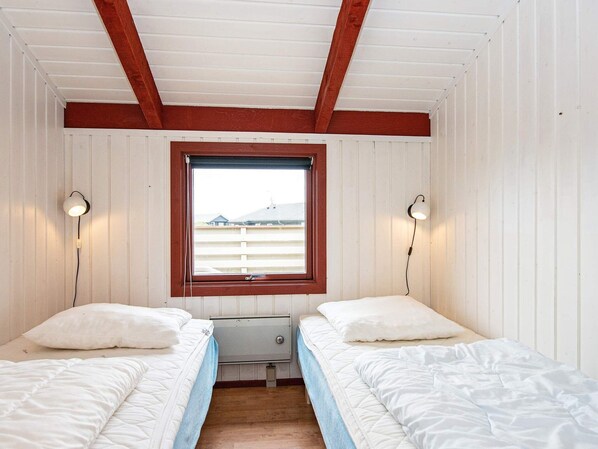 A twin room with two beds, a window, and two wall-mounted lamps.