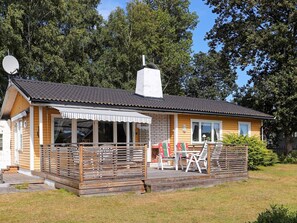 A wooden cabin with a covered patio, a chimney, and a satellite dish. - 4 Person Holiday Home in Askloster (Åskloster)