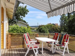 A wooden deck with a white table and two chairs, overlooking a fenced yard with greenery. - 4 Person Holiday Home in Askloster (Åskloster)