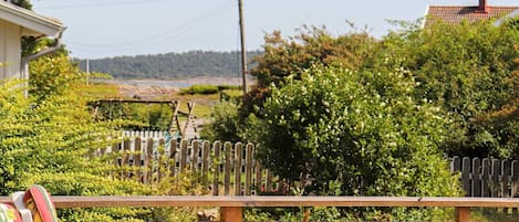A wooden deck with a bench, surrounded by greenery and a wooden fence.