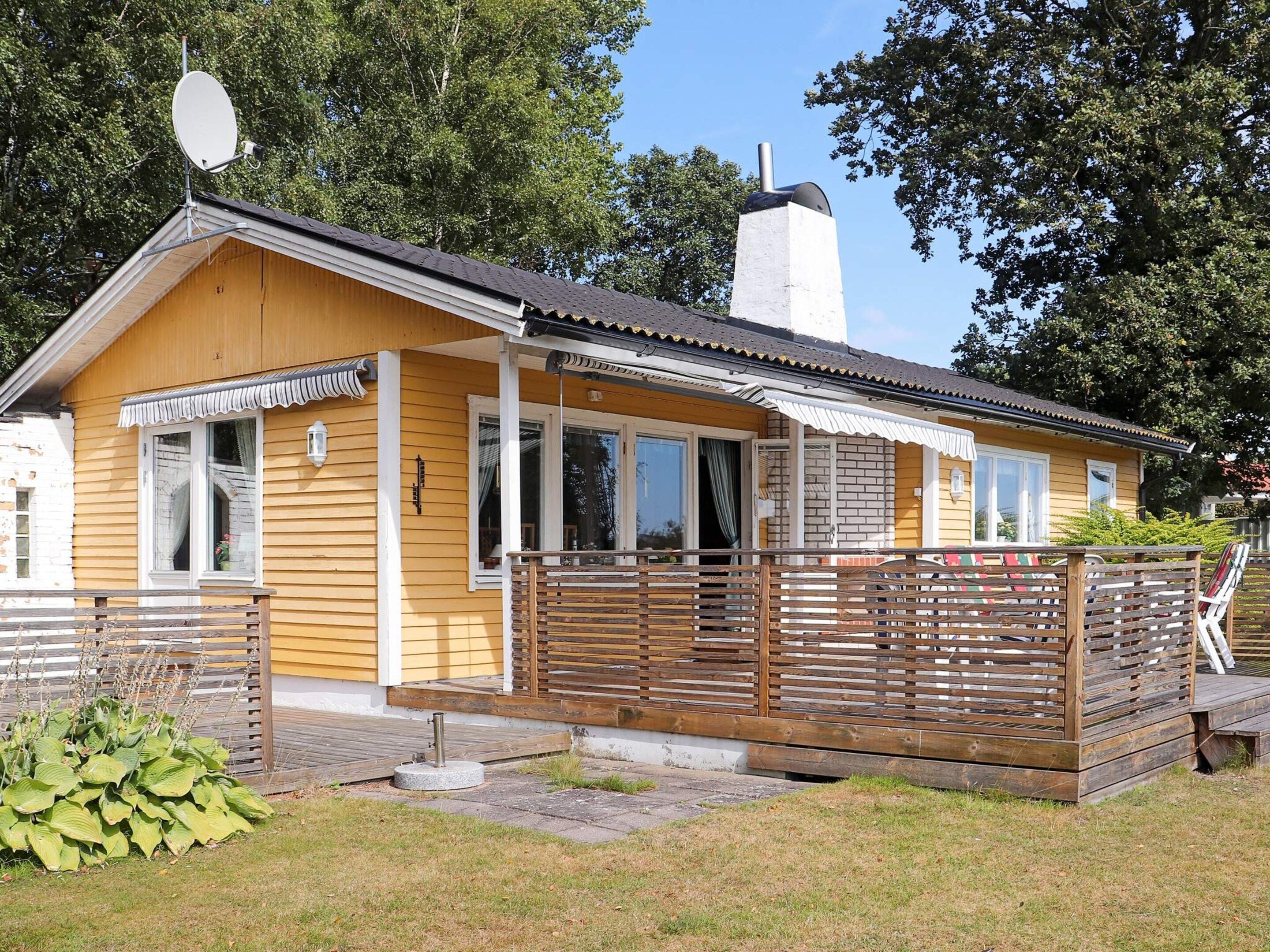 A wooden cabin with a balcony, a chimney, and a satellite dish.