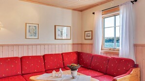 A cozy room with a red sofa, a wooden table, and a window with a view of the sea. - 6 Person Holiday Home in Brekstad-by Traum (Orland)