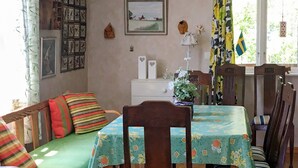 Un coin repas accueillant, avec une table en bois dressée pour quatre personnes, entourée de chaises. Un canapé vert agrémenté de coussins colorés est placé devant la table.