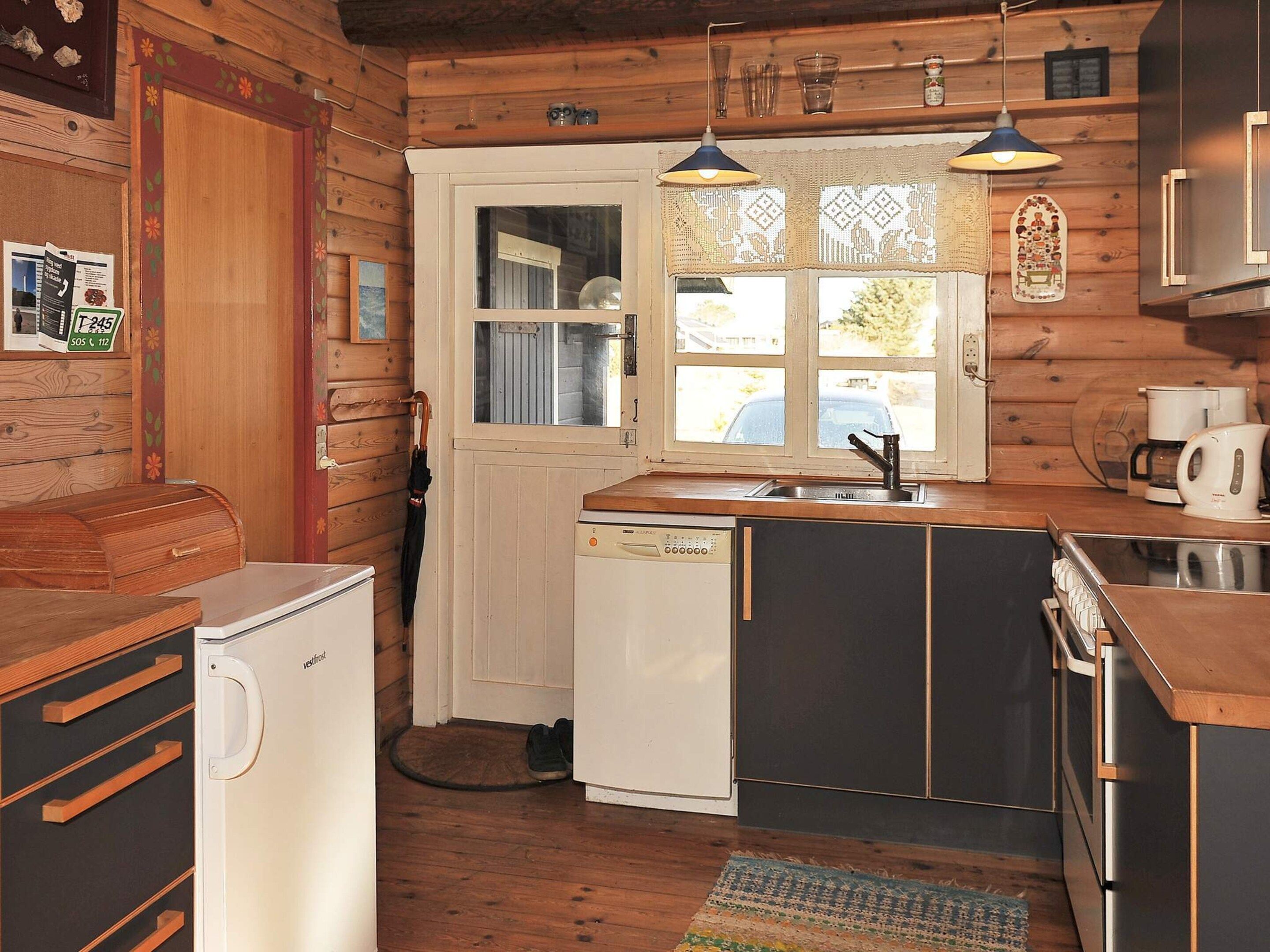 A compact kitchen with wooden walls, a sink, a dishwasher, and a coffee maker.