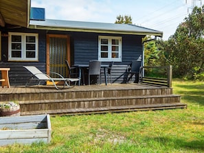 A wooden house with a porch, a table, and two chairs.