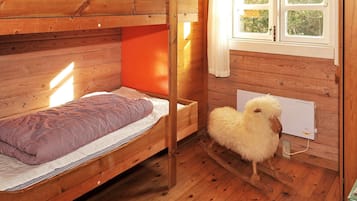 A wooden bunk bed room with a window and a fluffy white sheep toy.