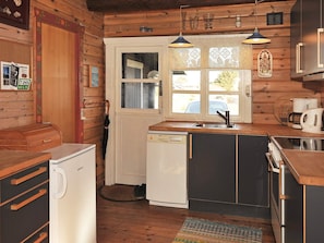 A compact kitchen with wooden walls, a sink, a dishwasher, and a coffee maker.