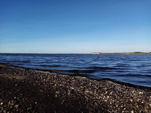 A beach with a rocky shoreline and calm sea. - 8 Person Holiday Home in Hojslev (Hojslev)