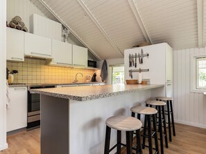 A kitchen with a central island, bar stools, a microwave, and a knife rack.