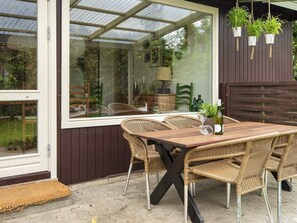 An outdoor patio with wicker furniture, a wooden table, and hanging plants. - 8 Person Holiday Home in Borkop (Borkop)