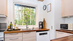 Ett modernt kök med inbyggd diskmaskin, kaffebryggare och mikrovågsugn.