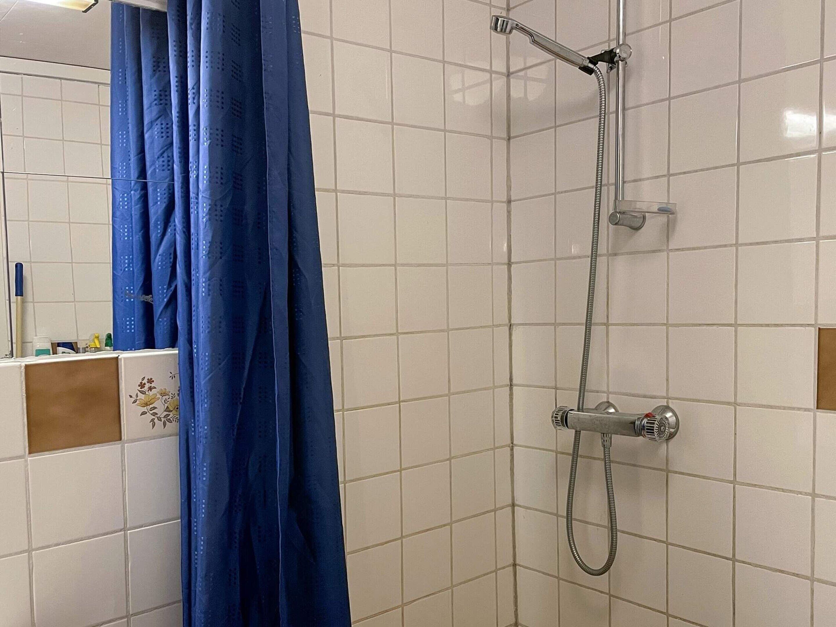 Une douche équipée d’un pommeau de douche à main et d’un robinet mural.