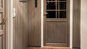 A wooden door with a window, a doorbell, and a light switch.