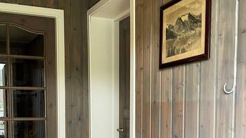 Ein Zimmer mit Holzwänden, einem gerahmten Bild an der Wand und einer Tür mit weißem Rahmen.