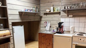 A compact kitchen with a white refrigerator, wooden cabinets, a coffee maker, and a stove.