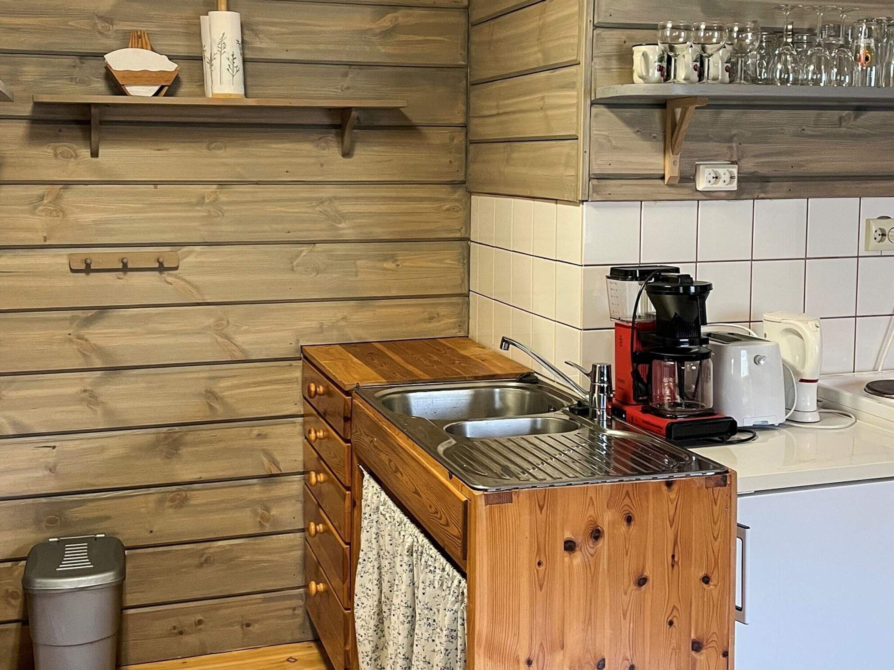 A kitchen with wooden cabinetry, a double sink, a coffee maker, and a toaster.