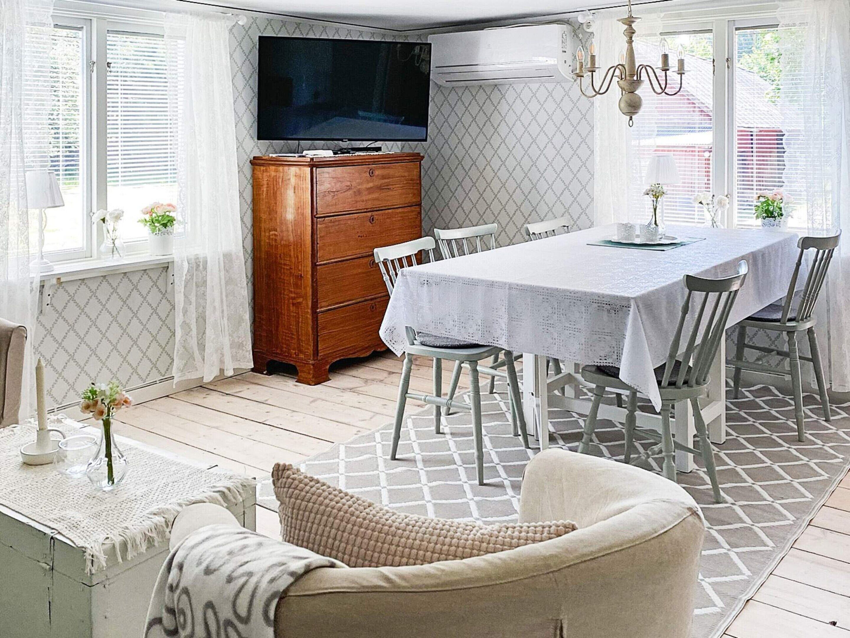 A dining area with a table set for four, a wooden cabinet, and a television mounted above the cabinet.