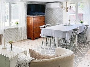 A dining area with a table set for four, a wooden cabinet, and a television mounted above the cabinet. - 5 Person Holiday Home in Haradsback (Ryd)