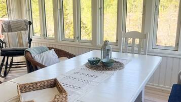 Un comedor con una mesa blanca, una cesta tejida y dos cuencos sobre un mantel individual.