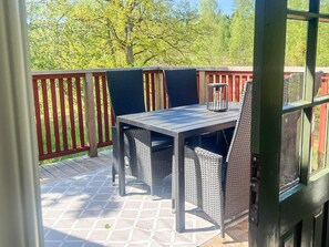 An outdoor patio with a table and chairs, a lantern, and a wooden deck.