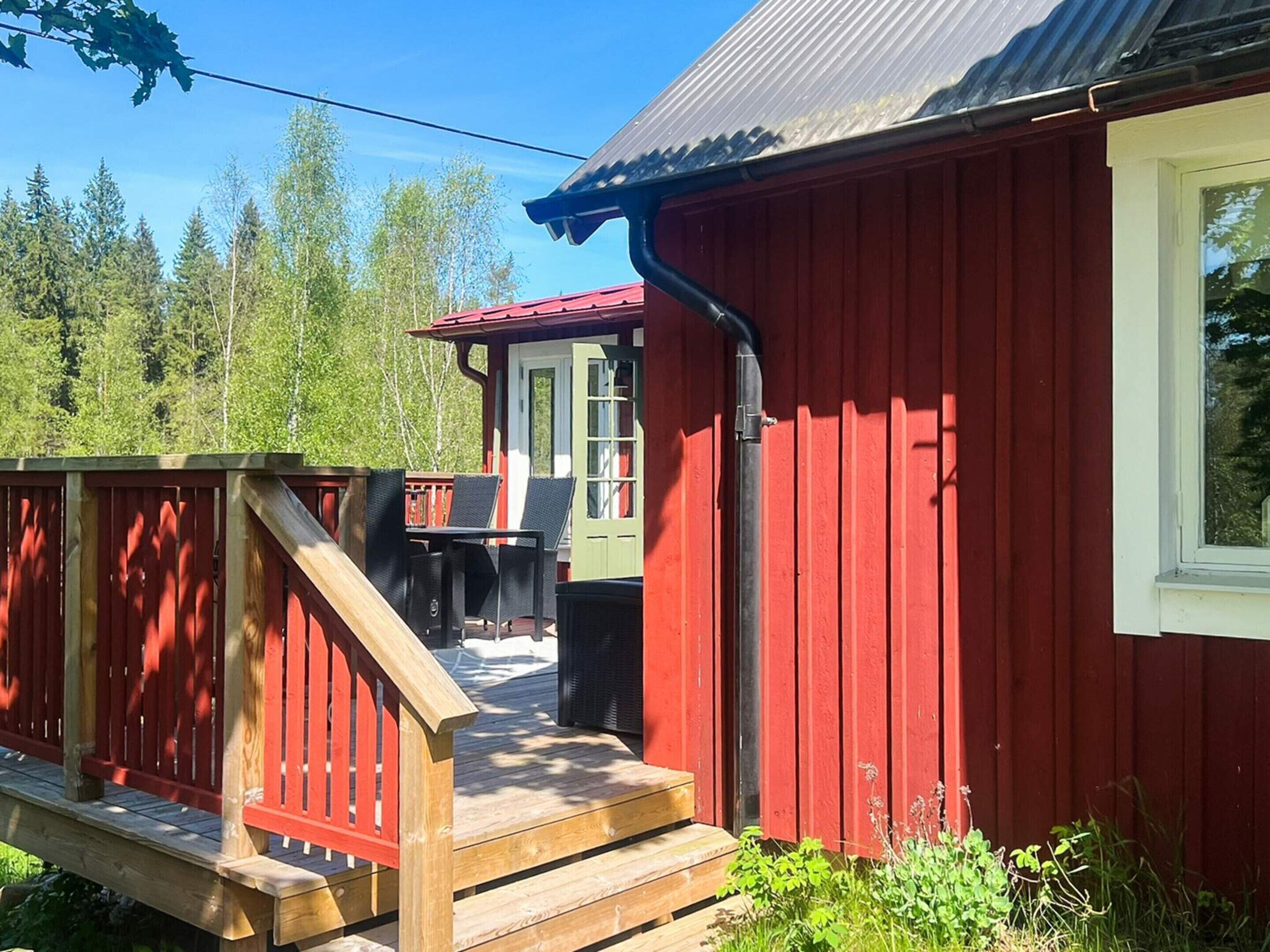 A red wooden building with a deck, a window, and a door.