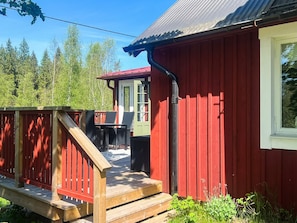 A red wooden building with a deck, a window, and a door. - 5 Person Holiday Home in Haradsback (Ryd)
