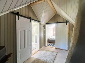 A loft bedroom with a high ceiling, a sliding door, a bed, and a small rug.