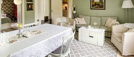 A dining area with a table set for two, a striped sofa, and a cabinet.