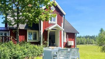 A red house with a white porch and a table with chairs.