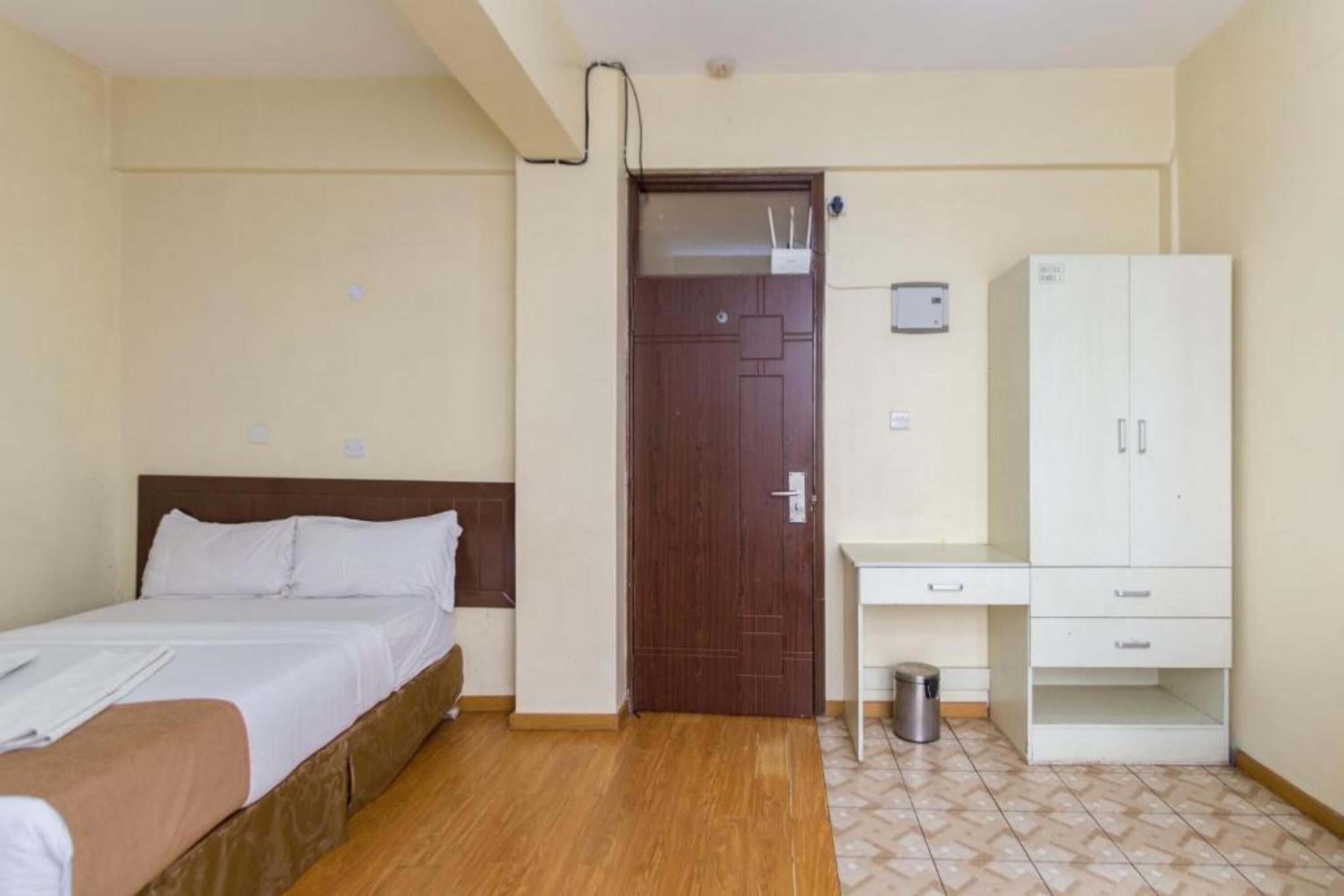 A hotel room with a bed, a desk, a wardrobe, and a door.