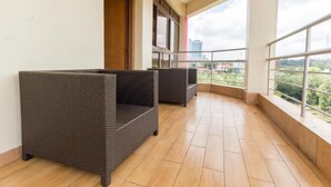 A balcony with wicker furniture, a tiled floor, and a view of the cityscape. - Cool Luxurious Studios (Nairobi)