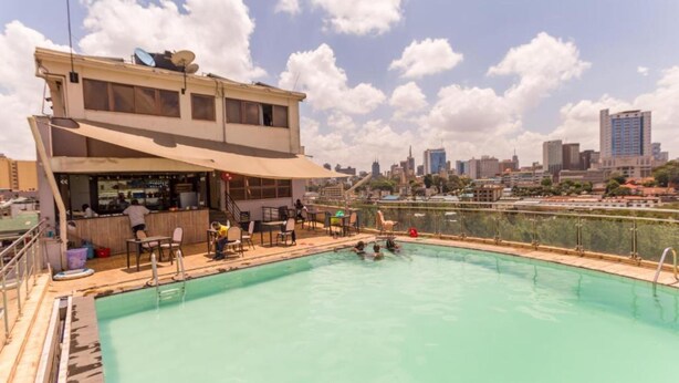 A rooftop swimming pool with a bar area, surrounded by city buildings. - Cool Luxurious Studios (Nairobi)