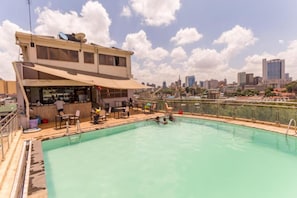 A rooftop swimming pool with a bar area, surrounded by city buildings. - Cool Luxurious Studios (Nairobi)